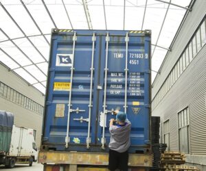 Workers loading rolls of toilet paper into a shipping container