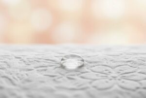 Close-up of a soft, delicately embossed facial tissue with a water droplet resting on its surface