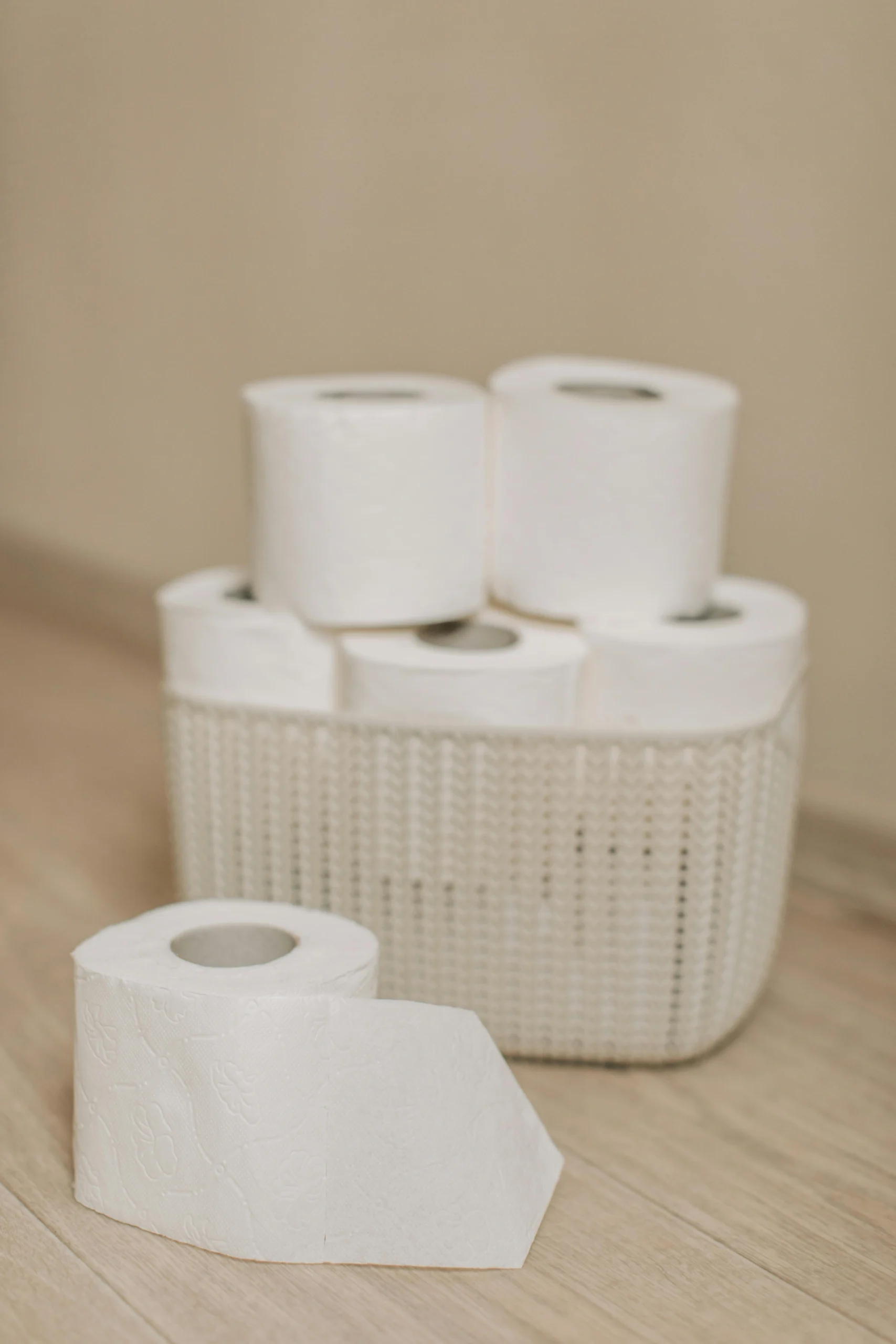 Collection of toilet paper rolls neatly arranged in a woven basket on a wooden floor