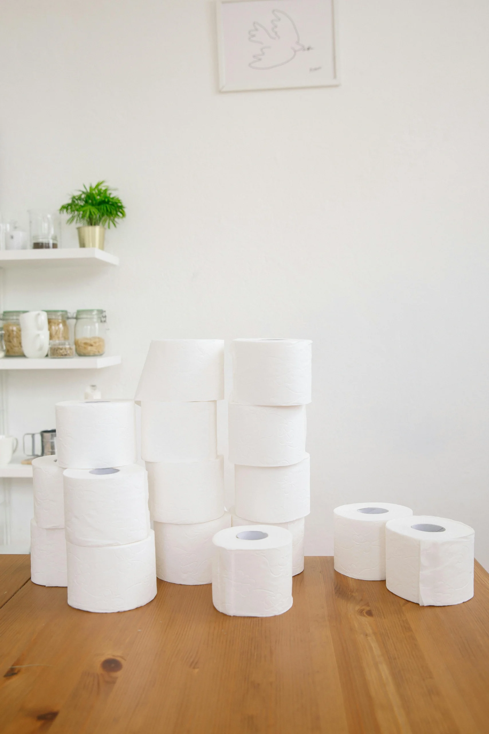 Stacked toilet rolls on wooden table in bright indoor setting with minimalist decor.