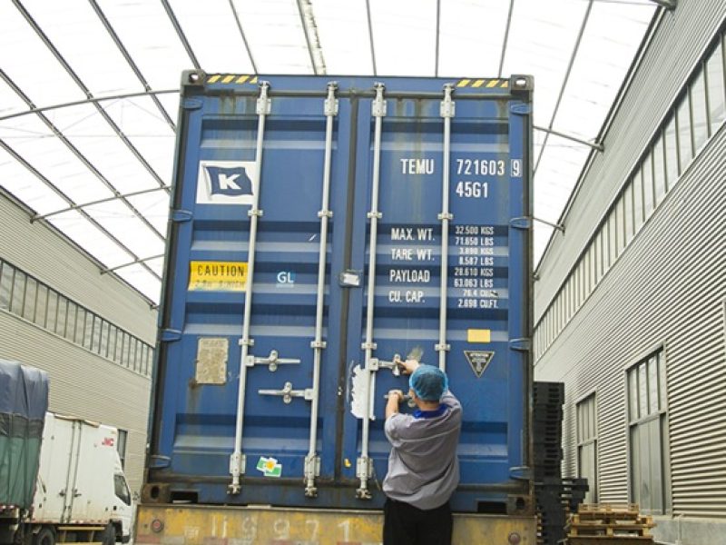 Workers loading rolls of toilet paper into a shipping container